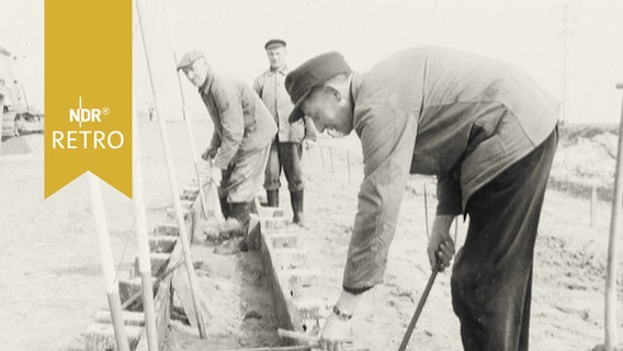 Mehrere Bauarbeiter beim Betonieren eines Grabens oder Längsschachtes 1965  