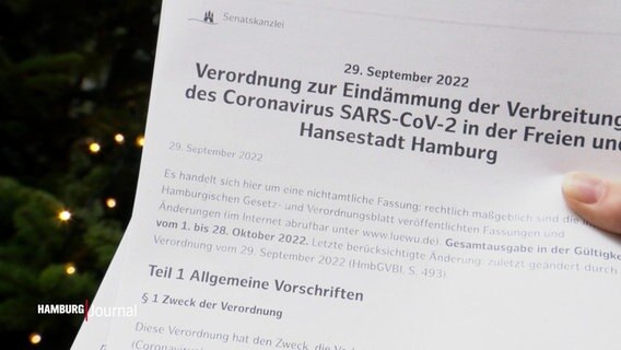 Eine Hand hält die Corona Eindämmungsverordnung für Hamburg. © Screenshot 