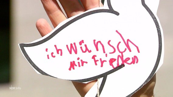 Ein Kind hat auf eine selbstgebastelte Taube den Spruch "ich wünsch mir Frieden" geschrieben. © Screenshot 