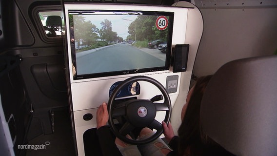 Eine junge Frau sitzt an einem Fahrsimulator. © Screenshot 