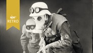Zwei Männer mit Gasmasken während einer Luftschutzübung (1963)  